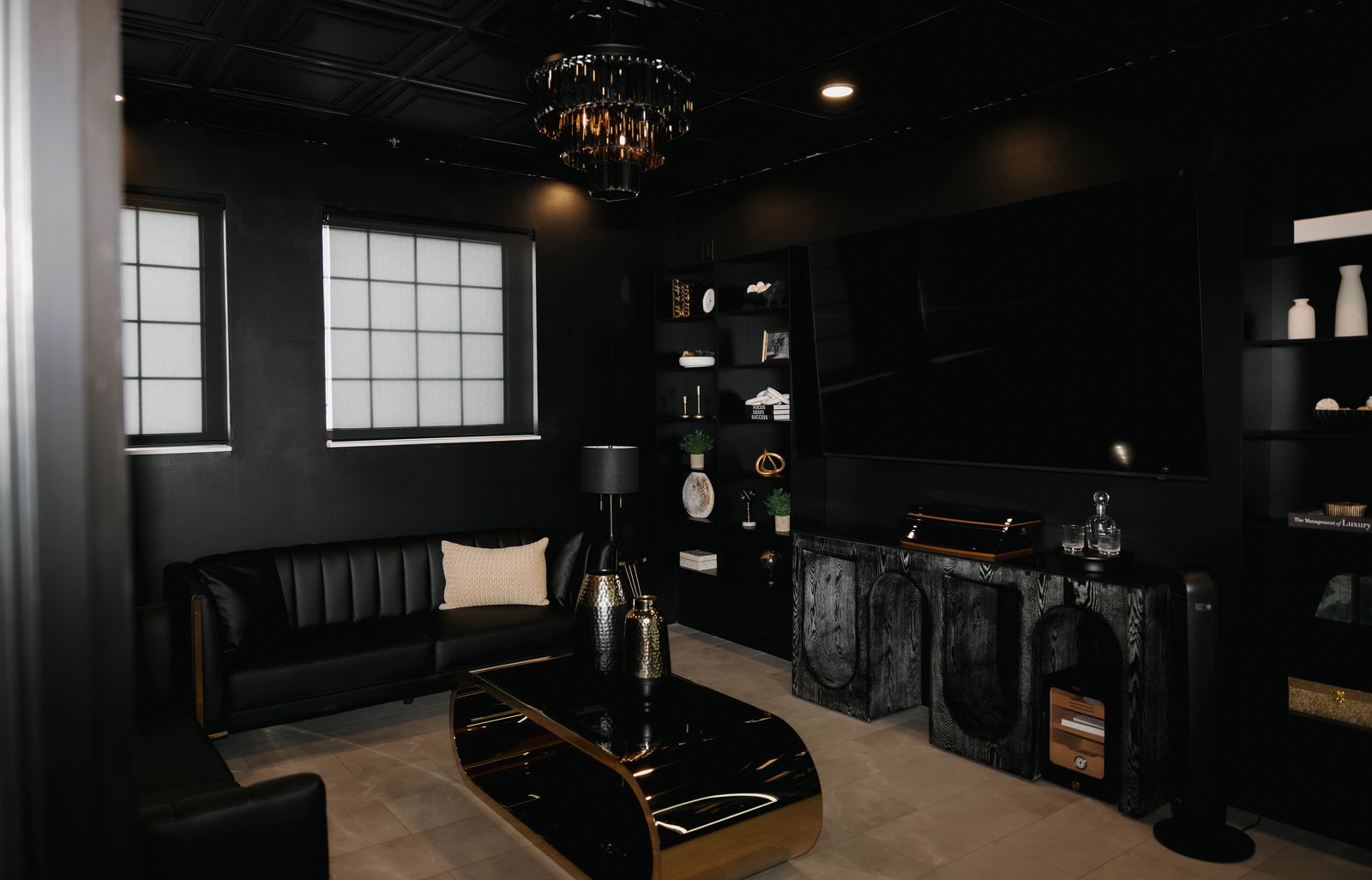 The black and gold VIP Suite at Trellis 925, with a leather sofa, crystal chandelier and gold coffee table